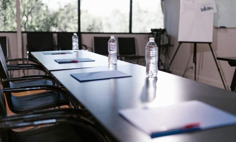Spacious conference room with water bottles and notes on a wooden table ready for a meeting.